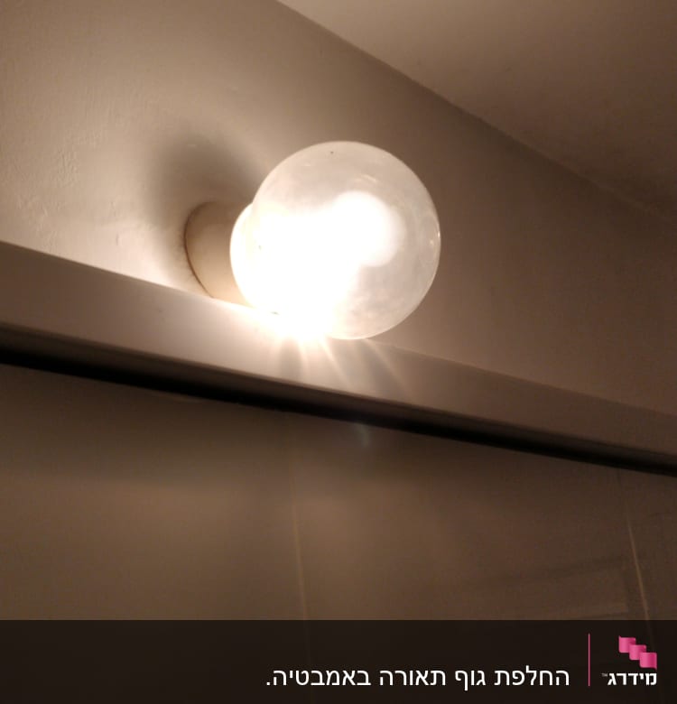 נורה עגולה דולקת על קיר לבן